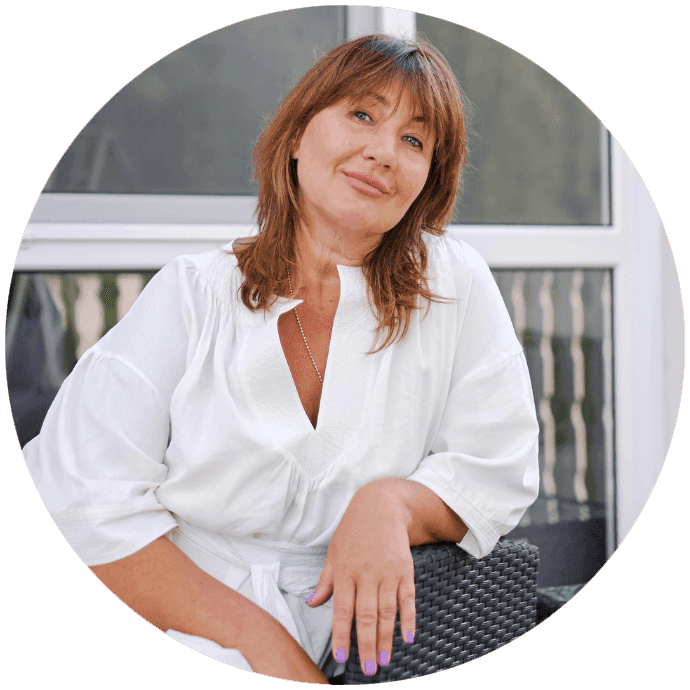 Eine Frau die entspannt auf einem Stuhl sitzt und lächelt.